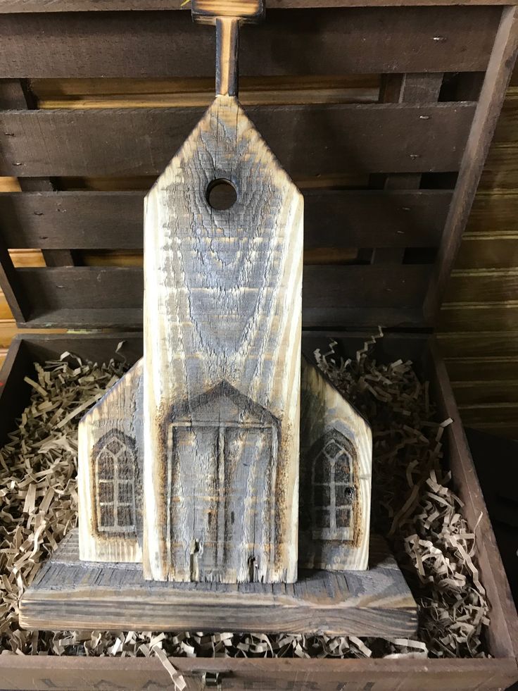 a small wooden church in a box filled with wood shavings