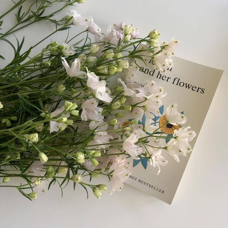 some flowers are laying on top of a book with the title and her flowers written in it