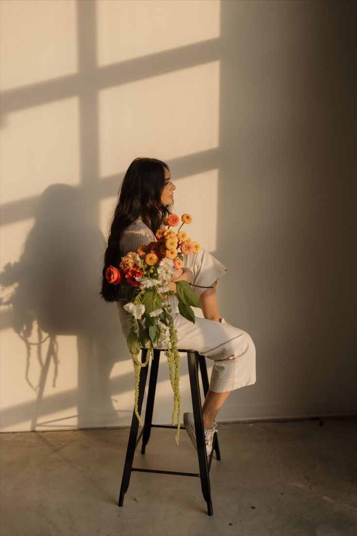 a woman sitting on a chair with flowers in her lap