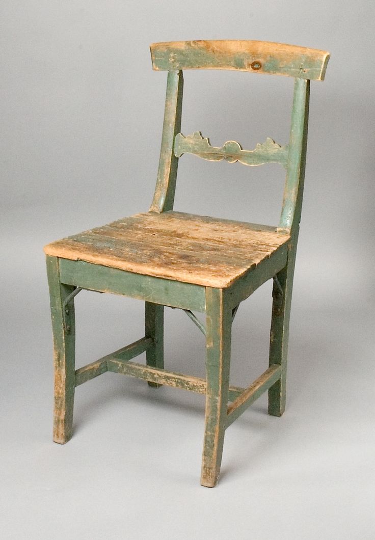 an old wooden chair sitting on top of a white floor next to a gray wall