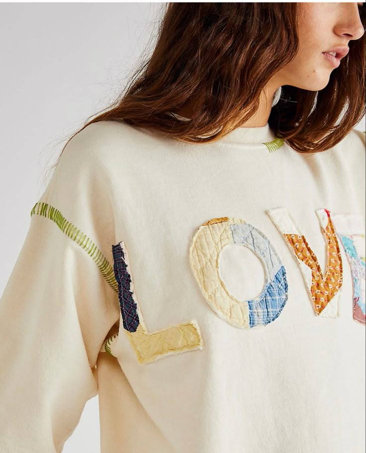 a woman wearing a sweater with the word love embroidered on it