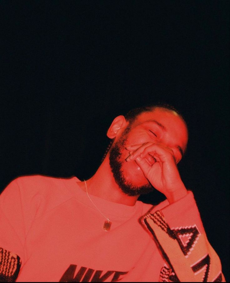 a man is laughing and holding his hands to his face while wearing an orange nike t - shirt