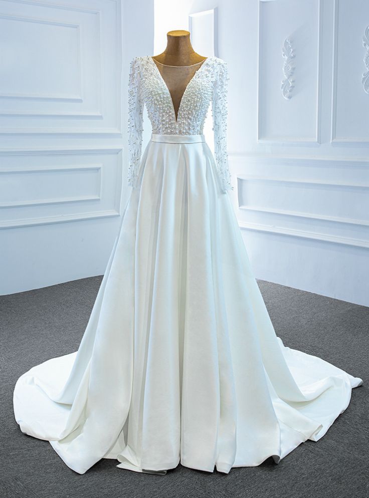 a white wedding dress with long sleeves on display