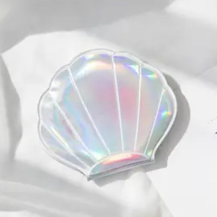 an iridescent shell shaped brooch sitting on top of a white sheet