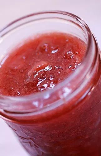 a jar filled with red liquid sitting on top of a white countertop next to a knife