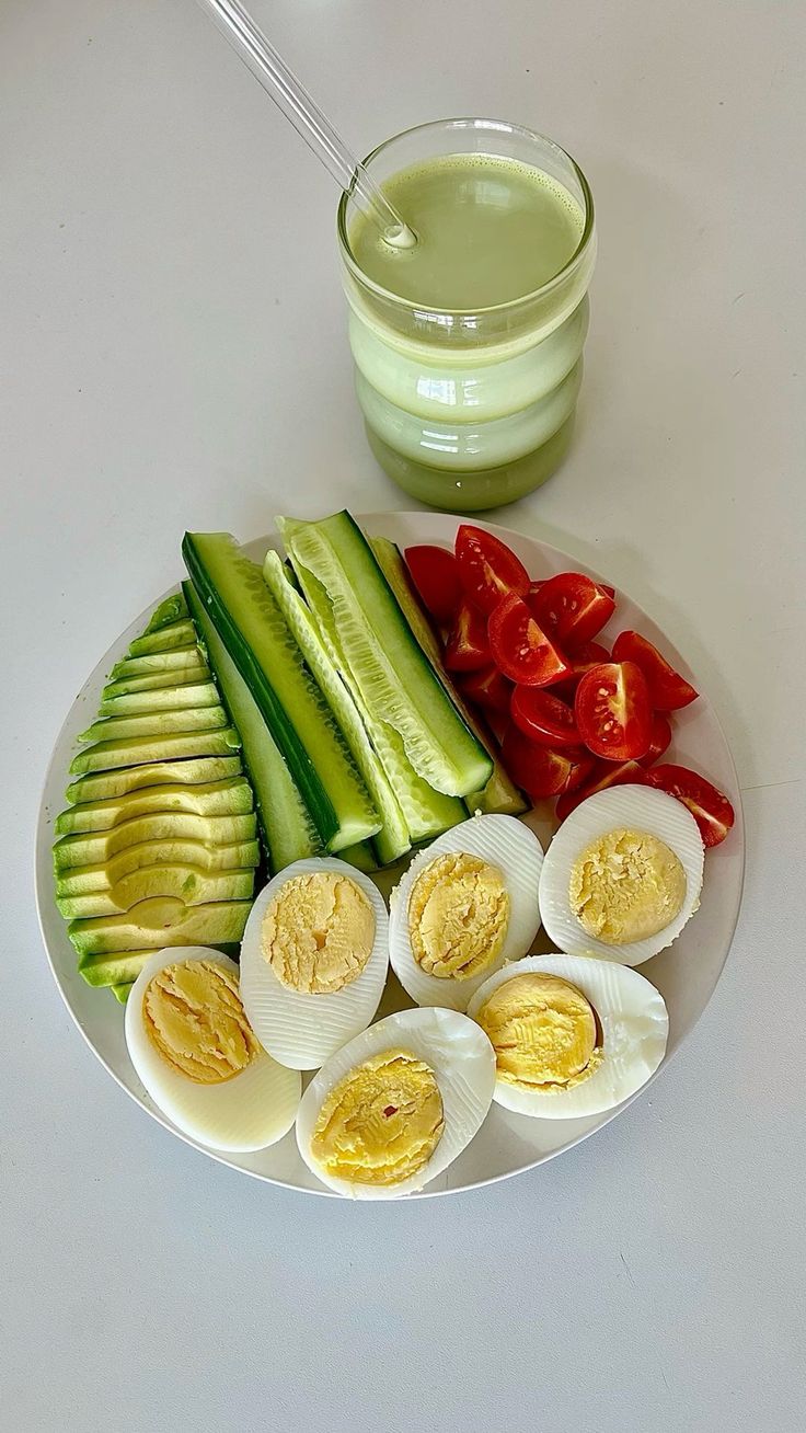 a plate with eggs, cucumbers, tomatoes and avocado on it