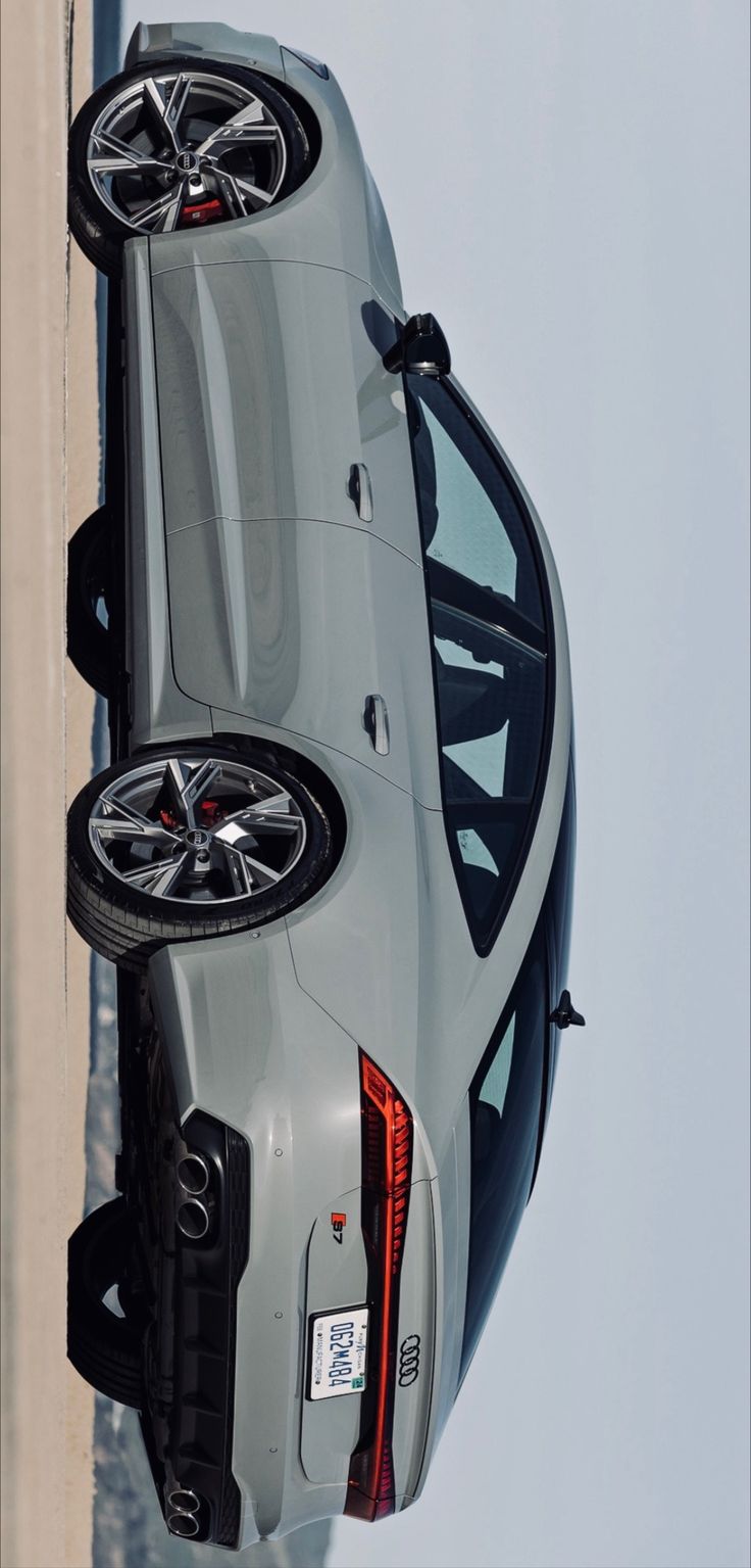 the rear end of a silver car with two wheels on it's rims