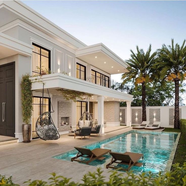 a house with a swimming pool and lounge chairs in front of the home's entrance