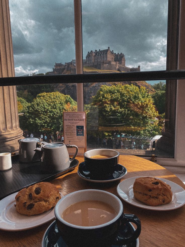 Teacups and scones on a table by a window, the view is overlooking Edinburgh Castle up on the hill on a sunny day. Scotland Aesthetic, Edinburgh Travel, Voyage Europe, I Want To Travel, Edinburgh Scotland, A Cup Of Coffee, Scotland Travel, Uk Travel, Travel Inspo