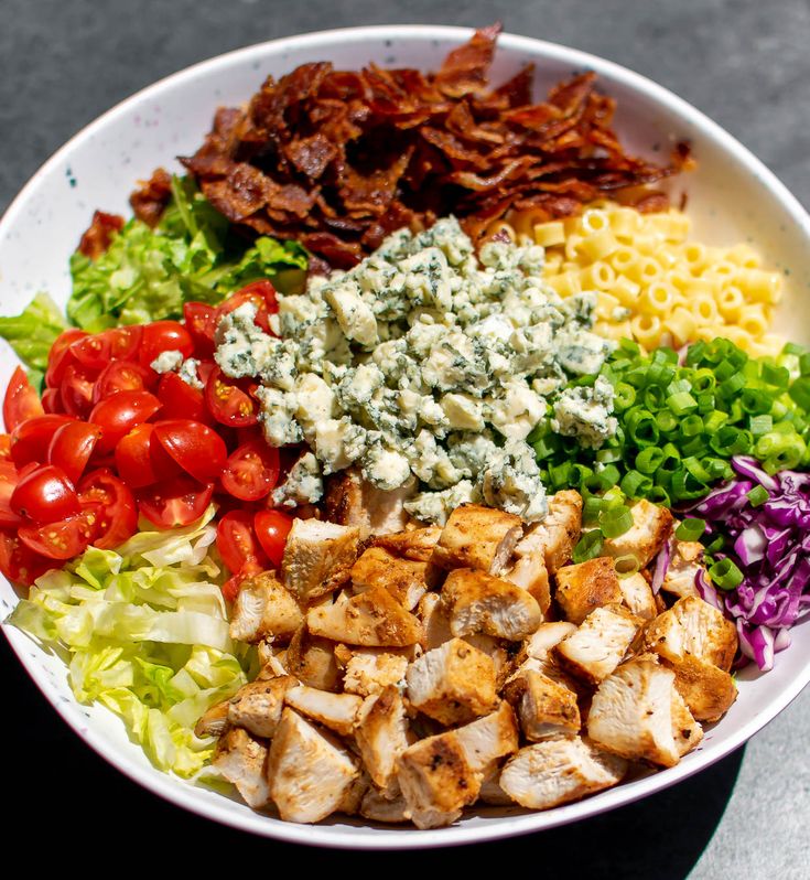 a white bowl filled with lots of different types of vegetables and meats on top of it