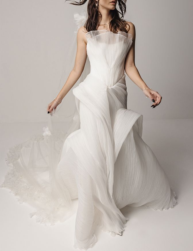 a woman in a white wedding dress is posing for a photo with her hair blowing in the wind