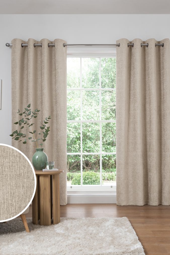 a living room with a couch, chair and large window covered in white drapes