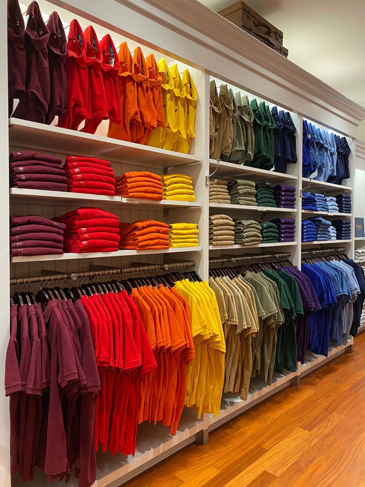 an assortment of colorful shirts on shelves in a store