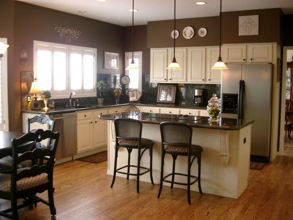 a large kitchen with white cabinets and black counter tops, along with wooden flooring