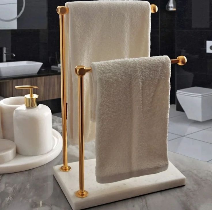 two white towels are hanging on a gold - plated towel rack