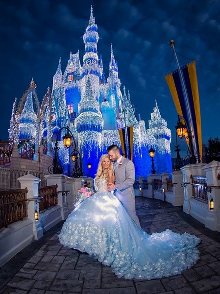 a bride and groom pose in front of the castle at night