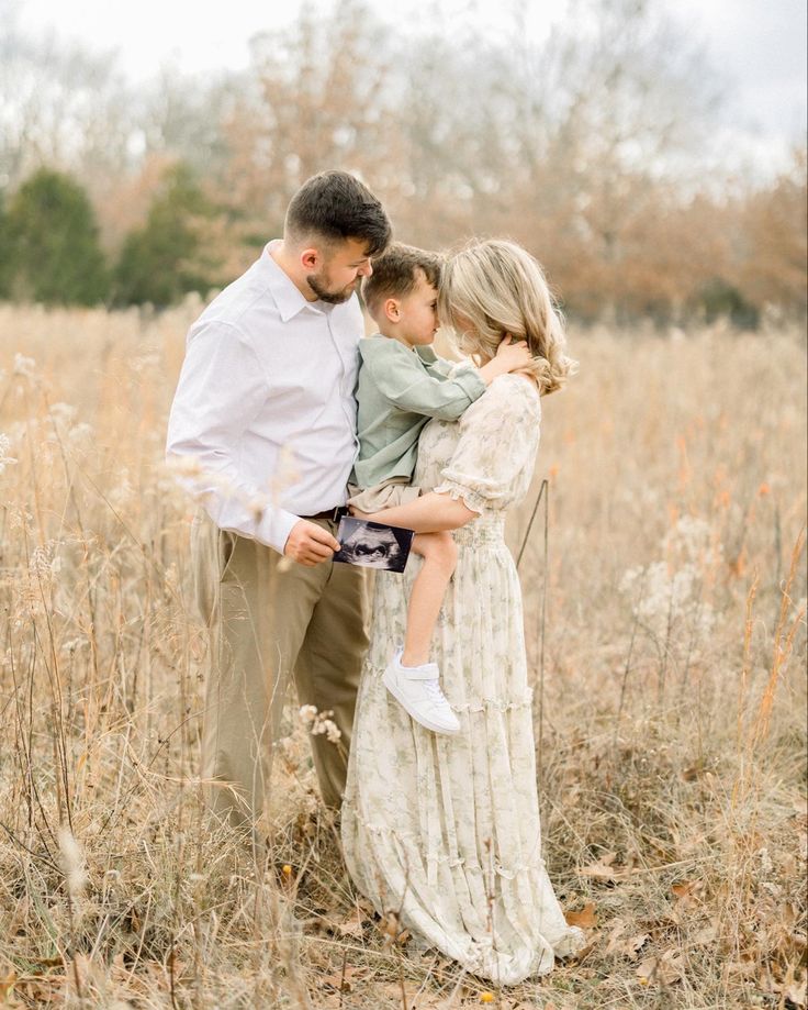 a man and woman holding a child in a field