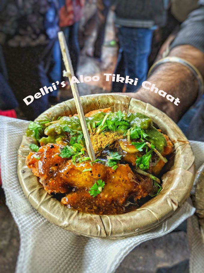 a person holding a bowl with food in it and the words delhi's aloo tibi chat