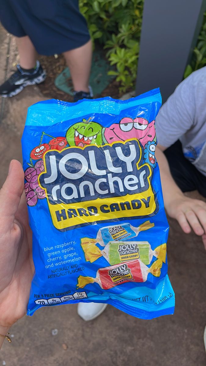 a person holding up a bag of jelly rancher hard candy in their left hand