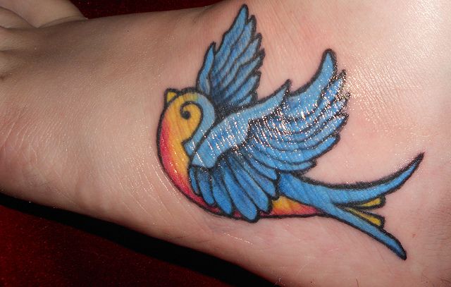 a colorful bird tattoo on the foot