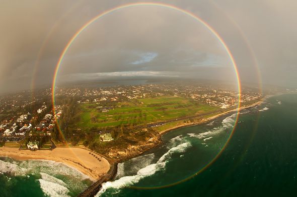 an aerial view of the ocean with two rainbows