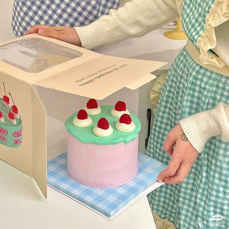 a woman is cutting into a cake with cherries on it and an open box behind her