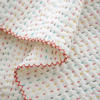 a white blanket with multicolored dots on it and a red line down the middle