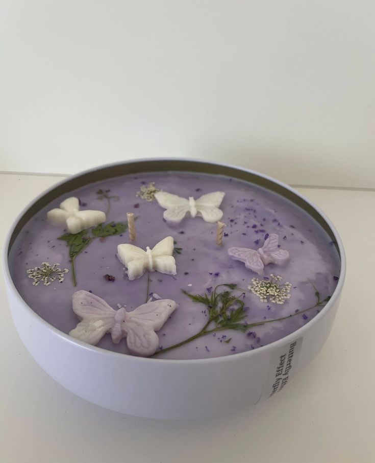 a white bowl filled with purple liquid and butterflies