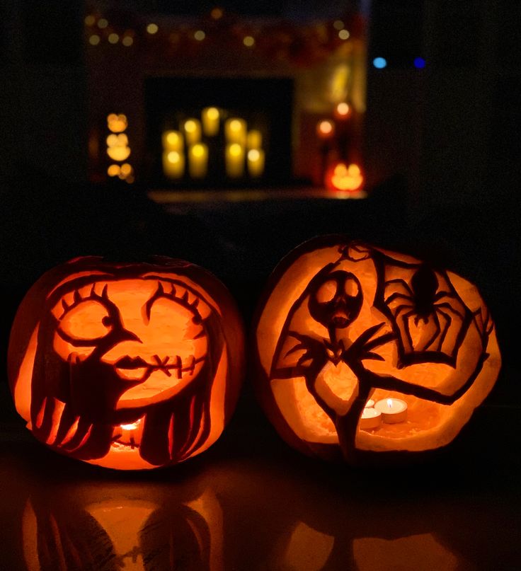 two carved pumpkins sitting on top of a table