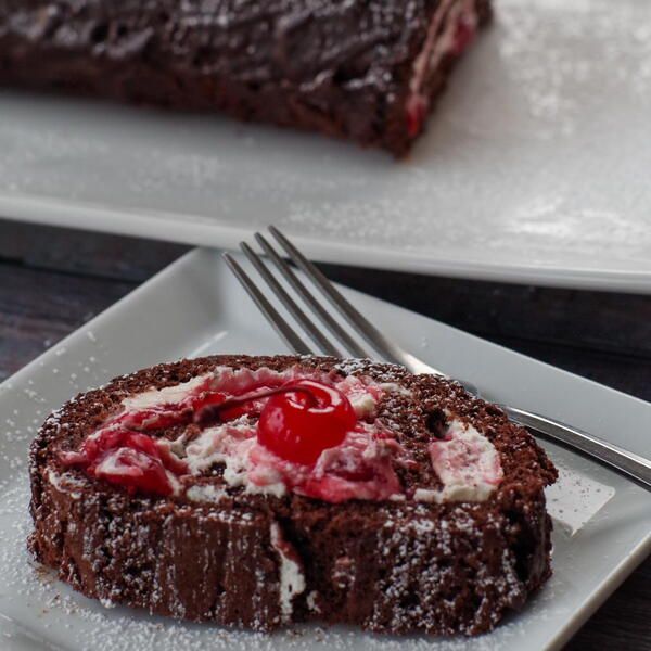 a piece of chocolate cake with cherries on it and a fork next to it