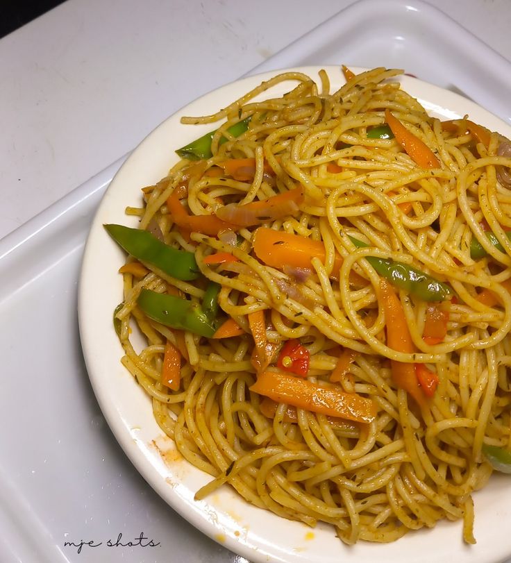 a white plate topped with noodles and vegetables