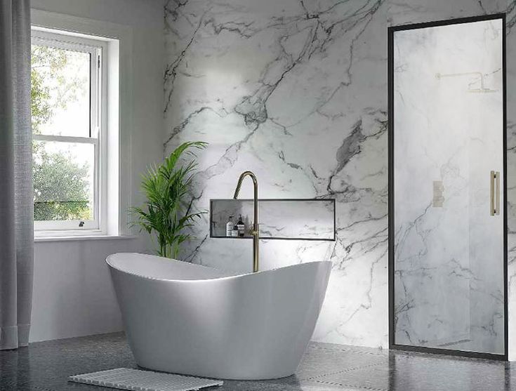 a white bath tub sitting next to a window in a room with marble walls and floors