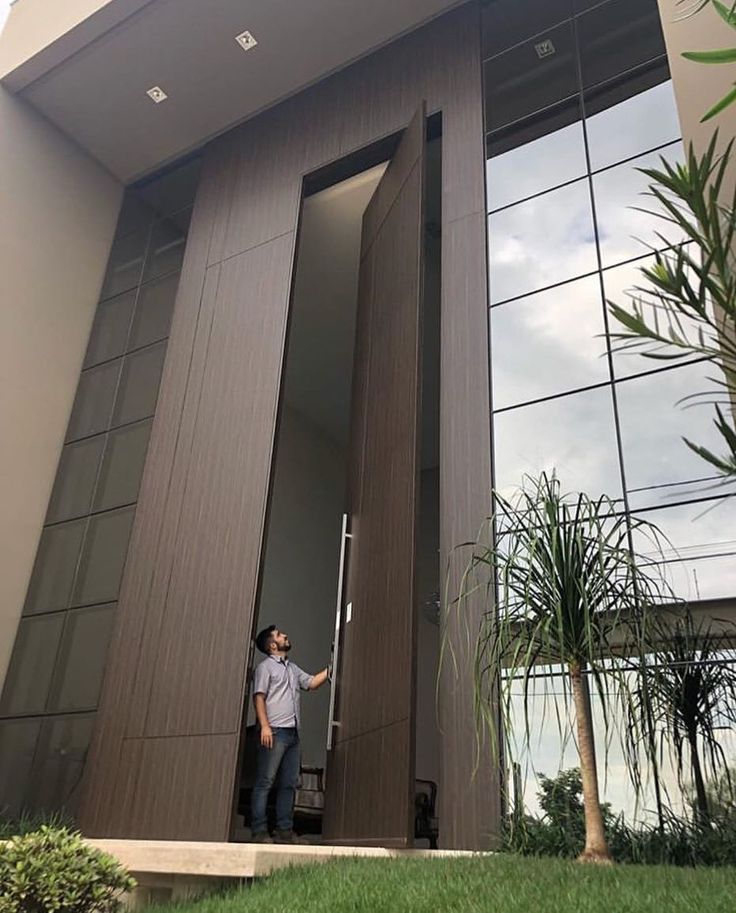 a man standing in the doorway of a modern house with his hand on the door handle