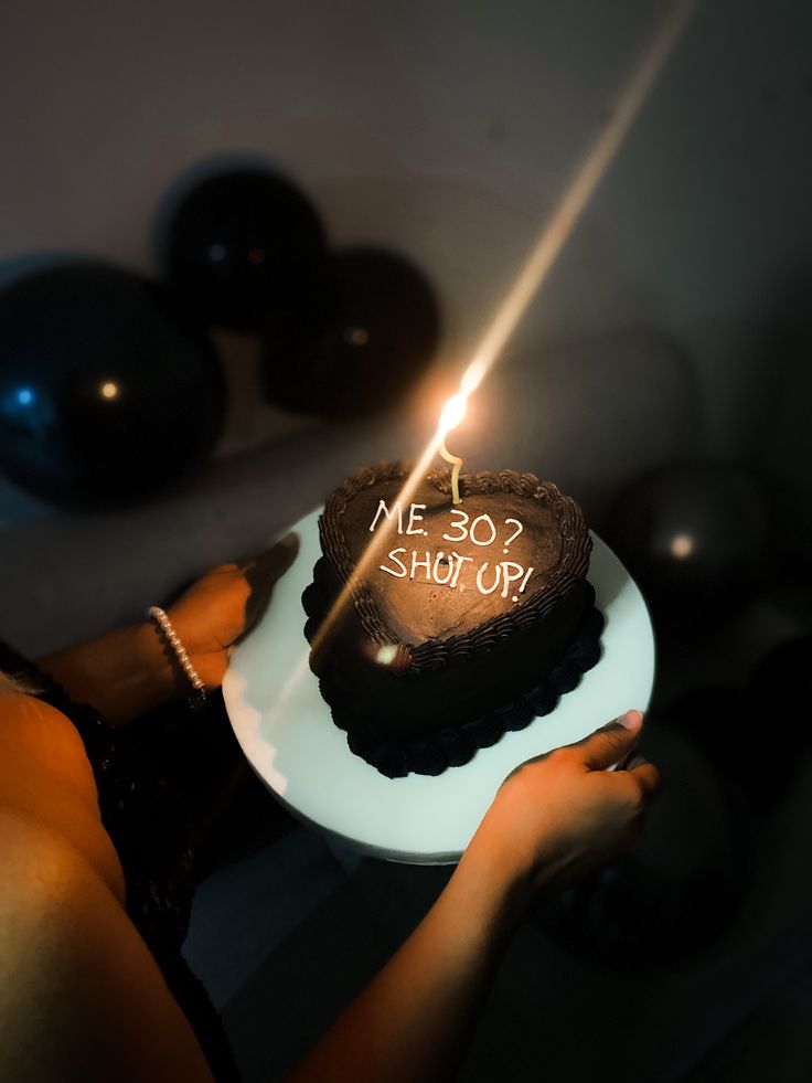 a woman holding a cake with the words me so short on it and a lit candle