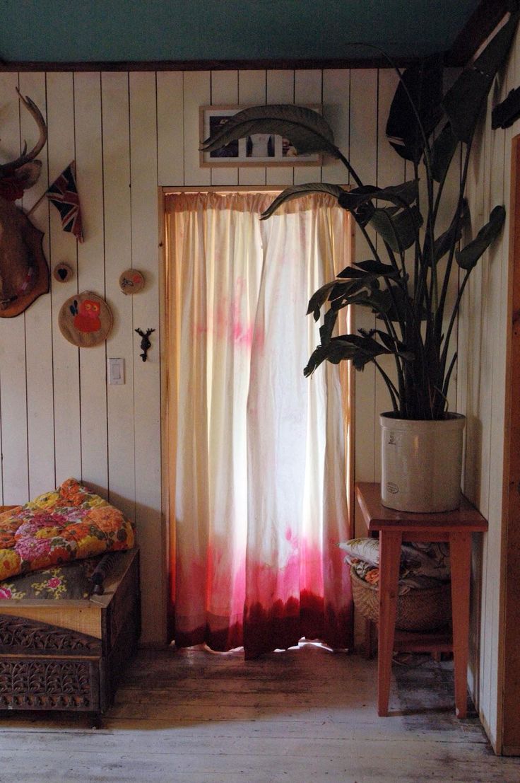 a living room filled with furniture and a potted plant next to a window covered in curtains