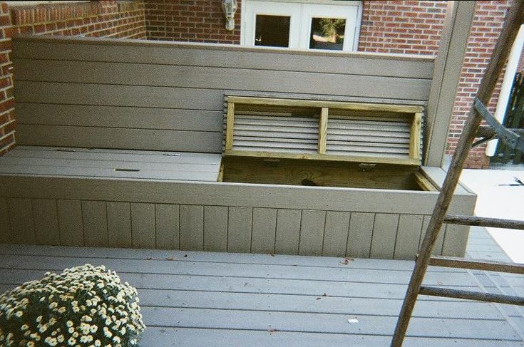 a wooden bench sitting on top of a hard wood floor next to a brick building