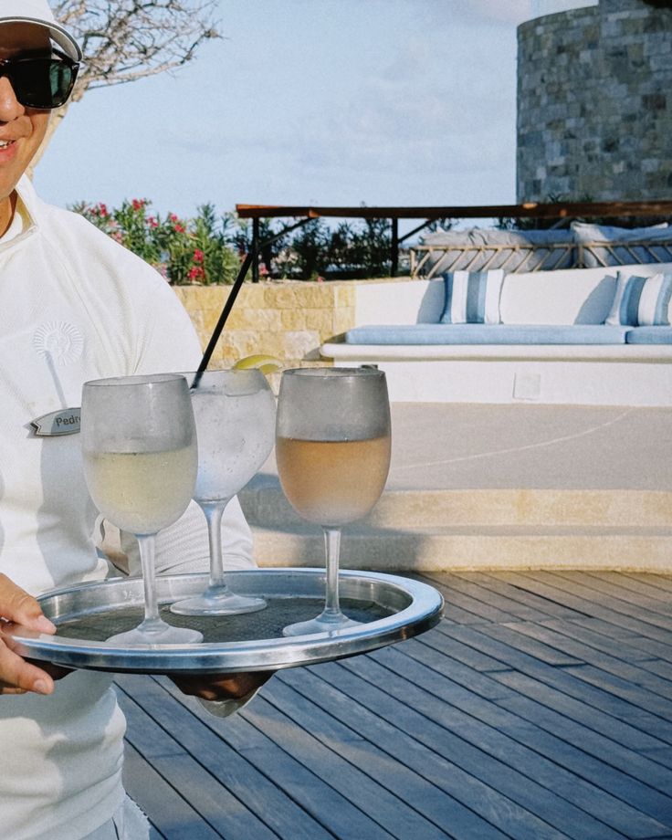 a woman holding two glasses of wine on a tray