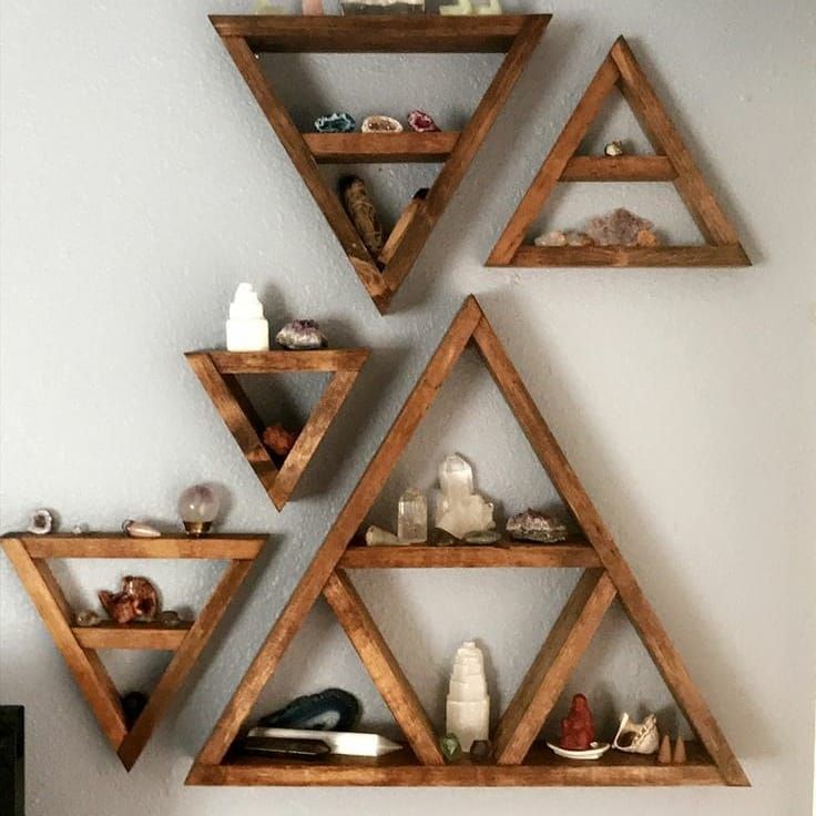 three wooden shelves on the wall with candles and other items in front of each shelf