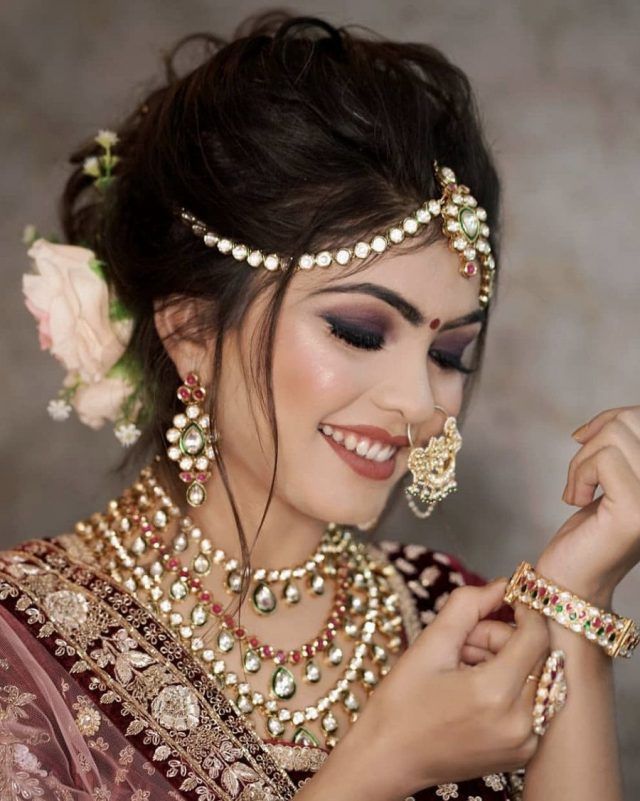 a woman in a bridal outfit with jewelry on her neck and hands holding onto the necklace