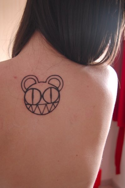 the back of a woman's shoulder with a bear tattoo on her left shoulder