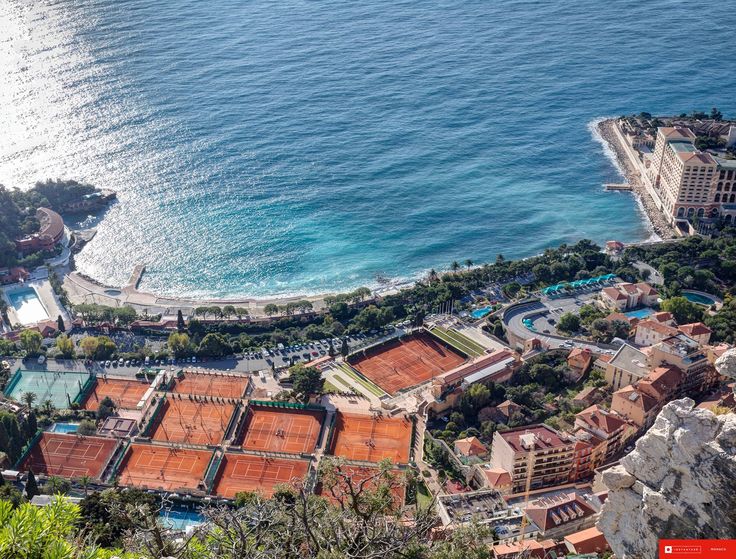 an aerial view of a tennis court in the ocean with buildings and trees around it