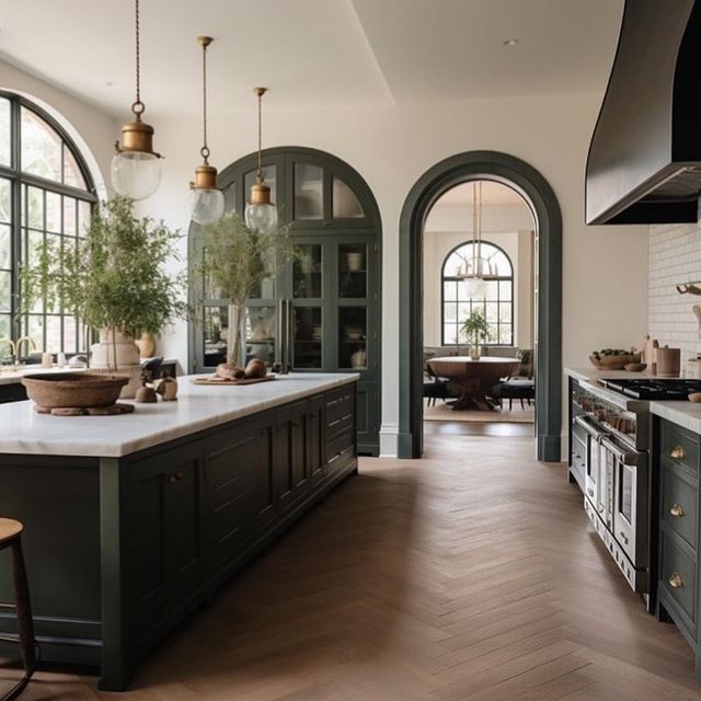 a large kitchen with an island and lots of counter space in front of two arched windows