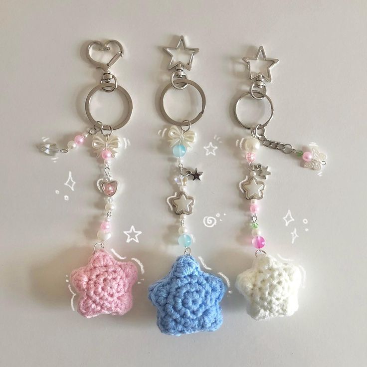 three crocheted key chains with charms attached to them on a white surface,