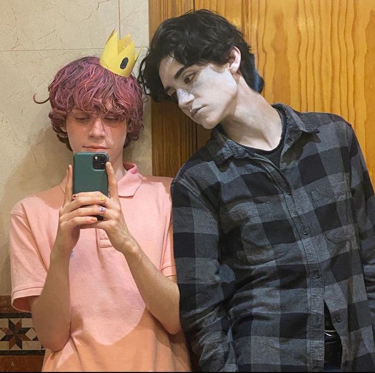 two people with face paint are looking at a cell phone