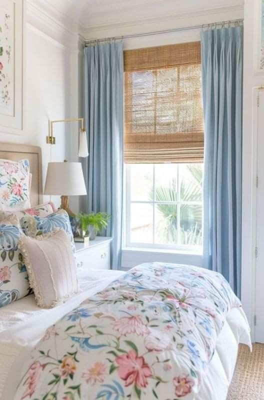 a bedroom with floral bedding and blue drapes on the window sill,