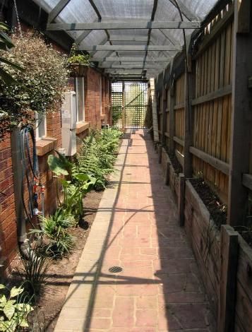 the walkway is lined with potted plants and brick walls, along with glass roofing