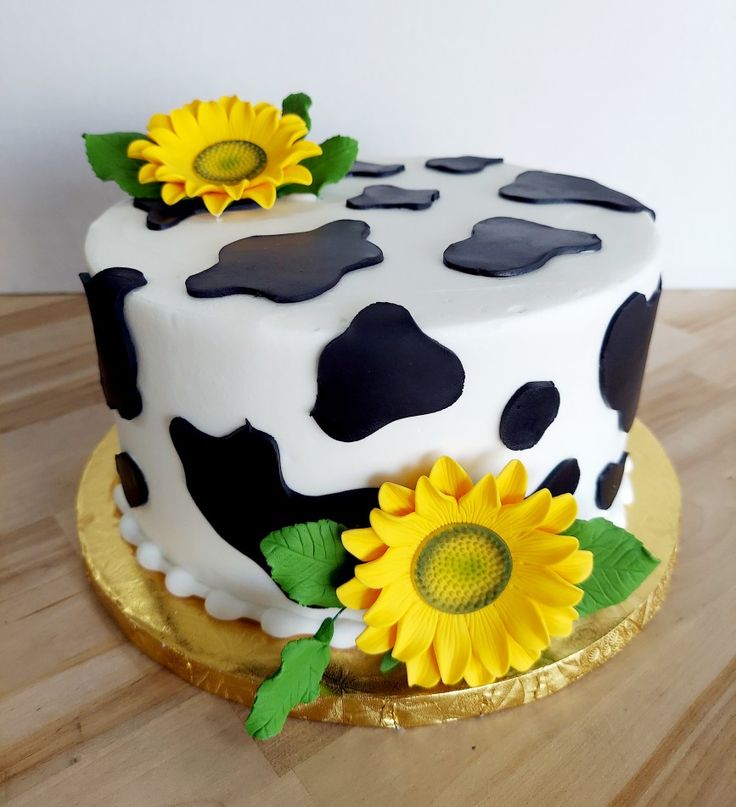 a cake decorated with black and white polka dots, sunflowers, and leaves