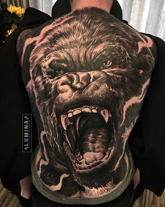 the back of a man's body with an angry gorilla tattoo on it, and his mouth open