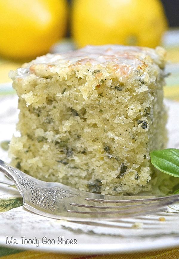 a close up of a piece of cake on a plate with a fork and lemons in the background