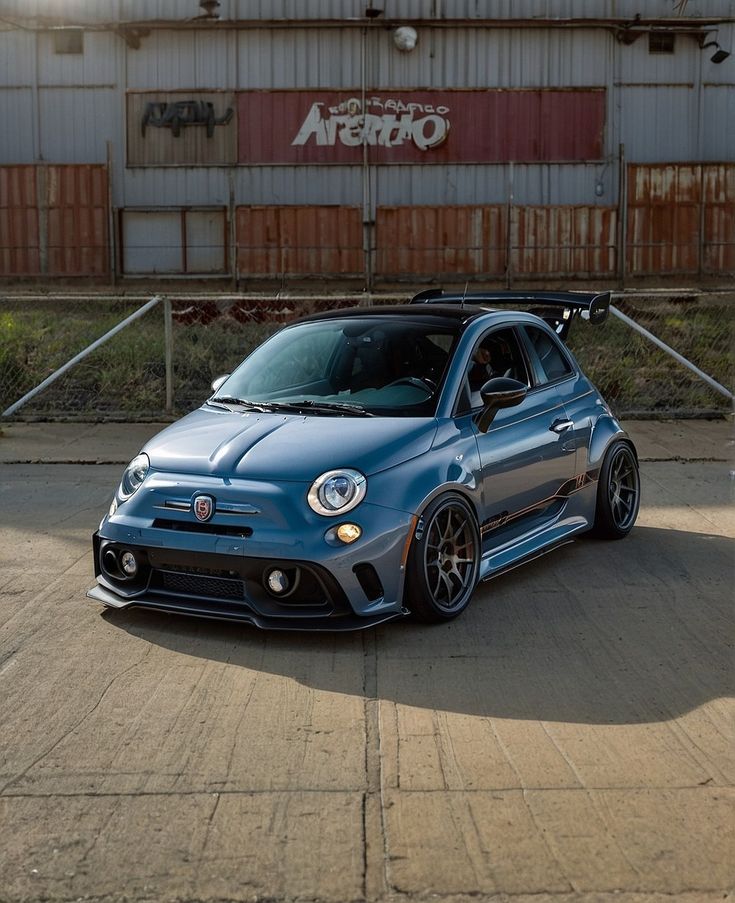 a small blue car parked in front of a building